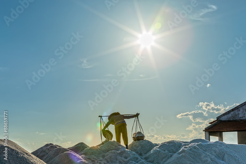 In Khanh Hoa, Vietnam, June 30, 2015: A farmer was carrying and pouring salt into piles on a sunny afternoon in the Hon Khoi salt field, Khanh Hoa, Vietnam photo