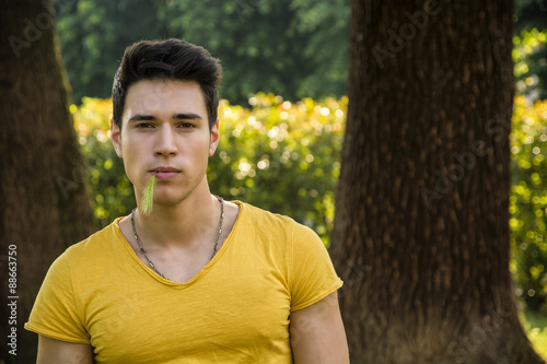 Attractive young man in park next to trees
