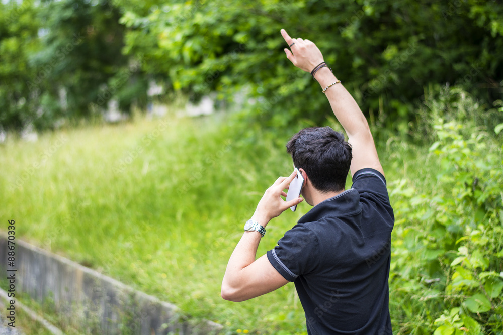 Young man on side of a road, calling and waiting for taxi Young man on side of a road, calling and waiting for taxi