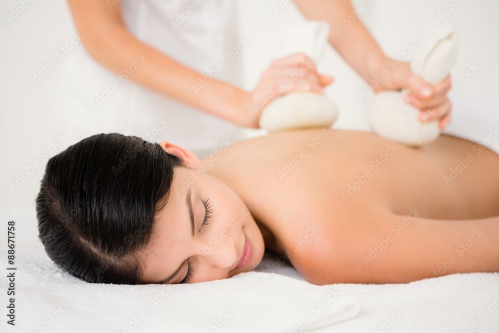 Pretty woman enjoying a herbal compress massage Pretty woman enjoying a herbal compress massage