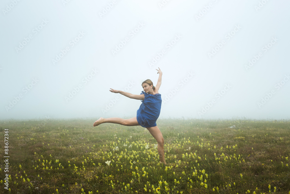 young caucasian female posing in blue dress in mountains in foggy weather young caucasian female posing in blue dress in mountains in foggy weather