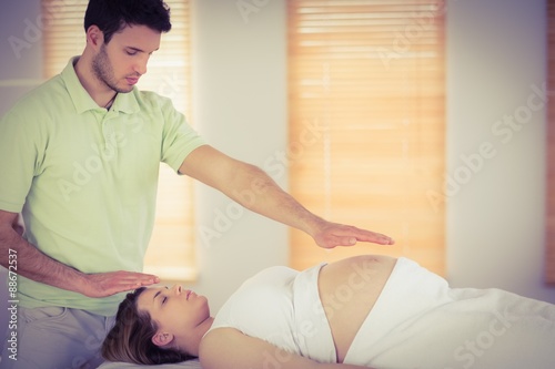 Relaxed pregnant woman getting reiki treatment