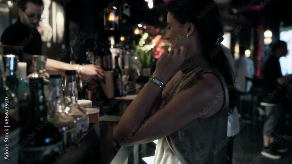 Woman standing and talking with bartender, steadycam shot
