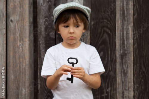 Cute little child, boy, holding big metal key, willing to unlock photo