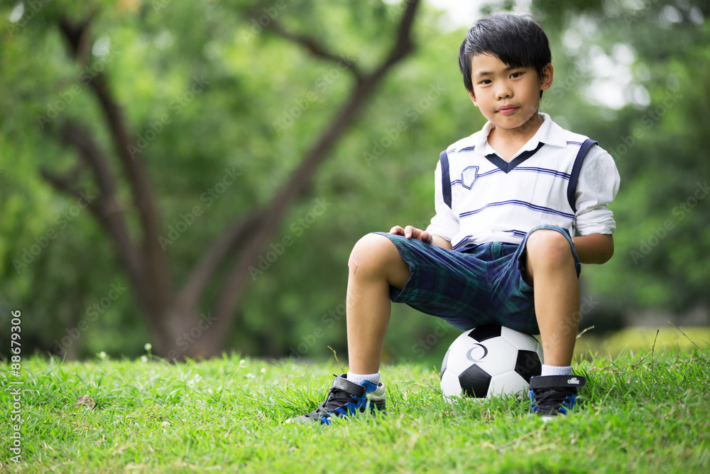 Little asian boy with football at the park Little asian boy with football at the park