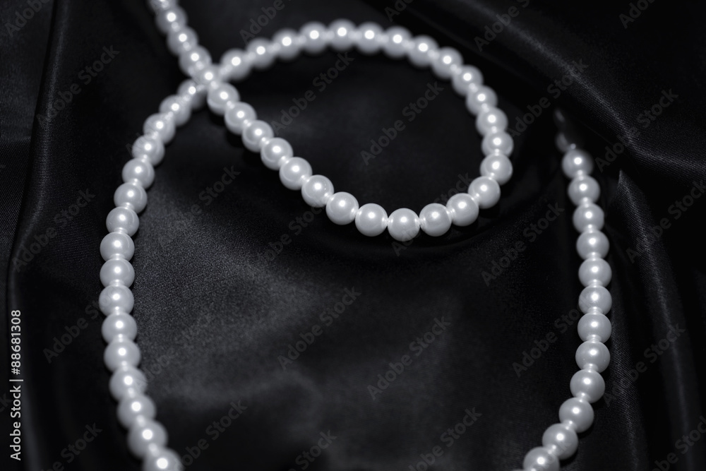 white pearl necklace on a black silk