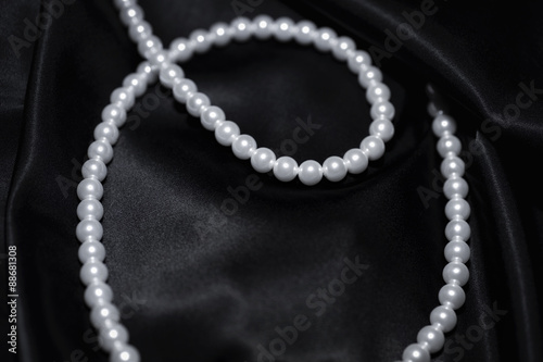 white pearl necklace on a black silk