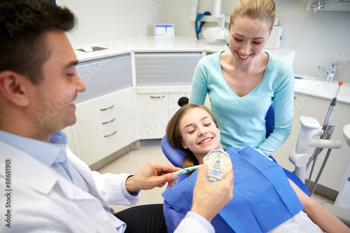 happy dentist showing toothbrush to patient girl