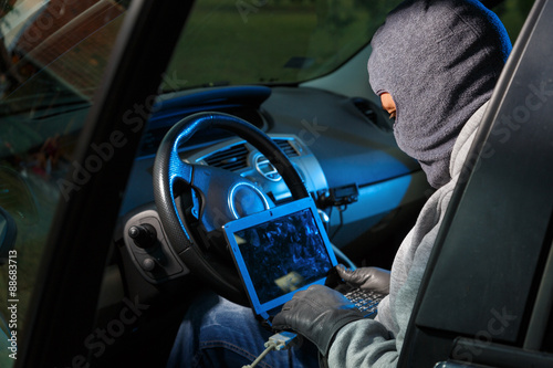 Obraz na plátne Car thief stealing a car. Hacking into the car system.