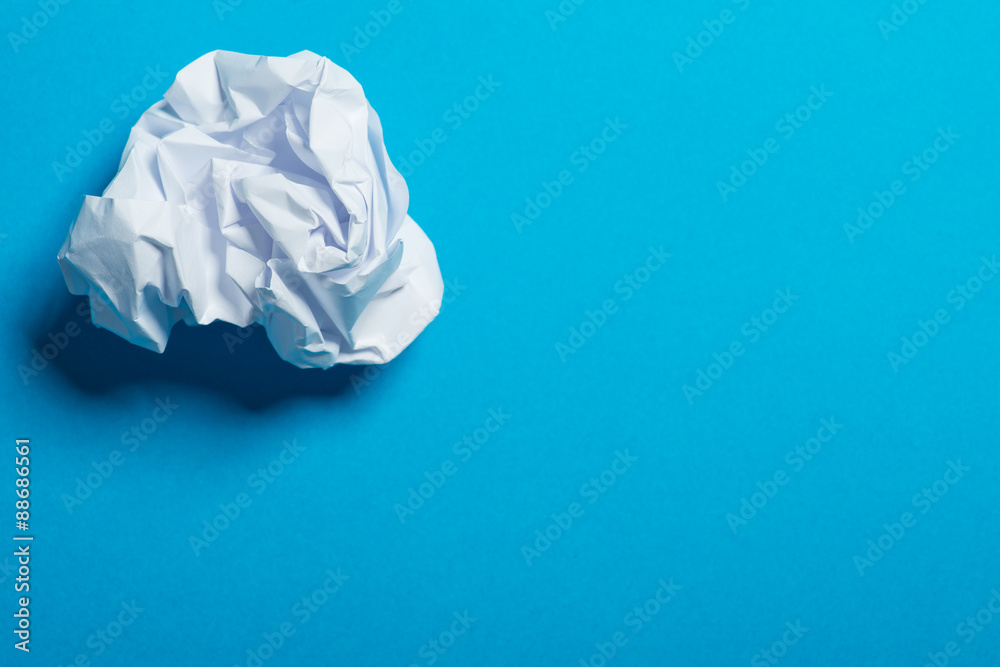 White color crumpled paper ball over the blue background