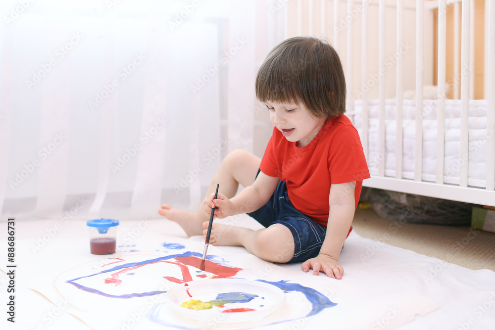 Little lovely child paints with brush and gouache Little lovely child paints with brush and gouache