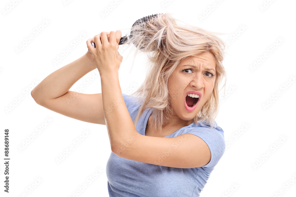 Upset woman with her hair tangled in a hairbrush Upset woman with her hair tangled in a hairbrush