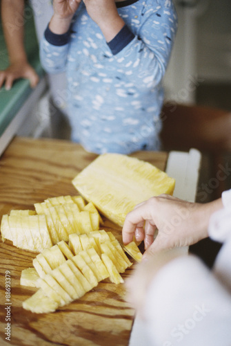 Woman cutting a fresh pineapple for her children. photo