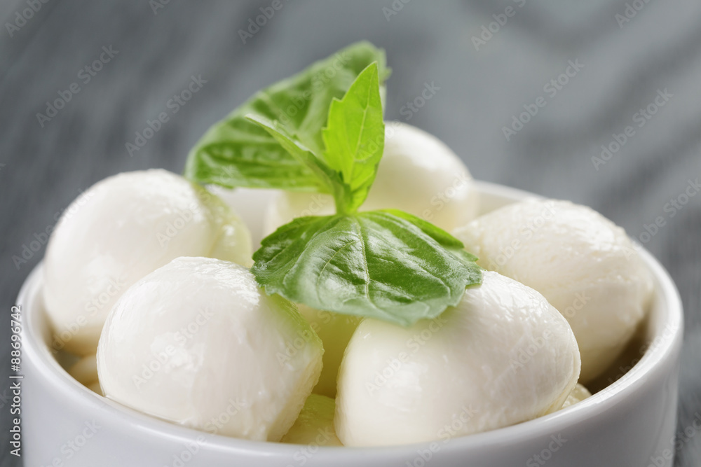 small balls of mozzarella in bowl with basil