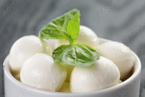 small balls of mozzarella in bowl with basil