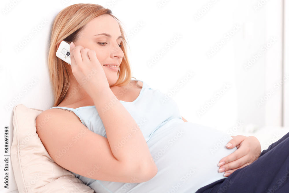 Pregnant woman talking per mobile phone in bed Pregnant woman talking per mobile phone in bed