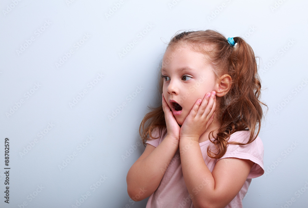 Surprising kid girl with opened mouth and hand near face looking Surprising kid girl with opened mouth and hand near face looking