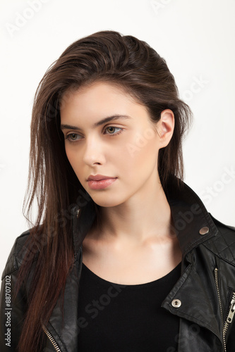 Emotive closeup portrait of a young naughty attractive brunette woman posing for model tests in black leather jacket