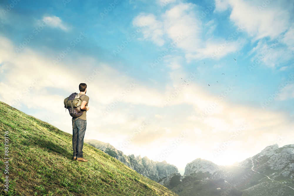 Man downhill observing mountain landscape at sunset