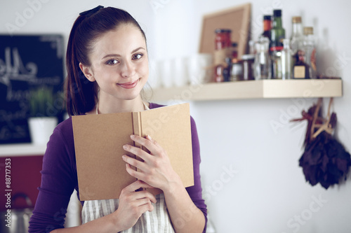 Young woman reading cookbook in the kitchen  looking for recipe