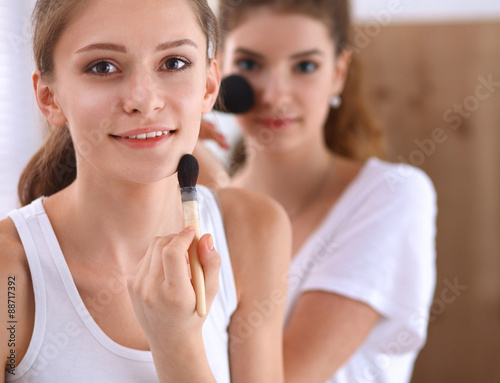 Beautiful girls looking in the mirror and applying cosmetic with