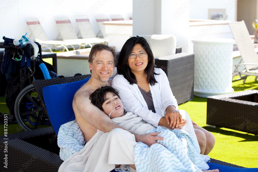 Father and mother with disabled son on blue lounger off side of Father and mother with disabled son on blue lounger off side of