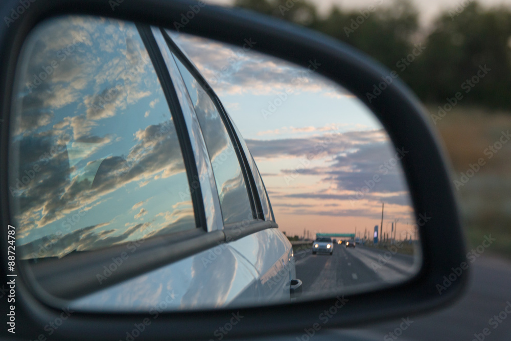 Side view car mirror reflection of sunset