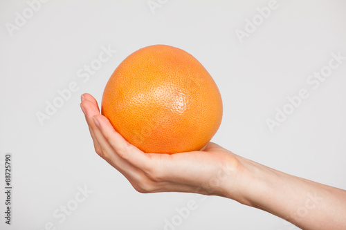 Female hand holding a ripe grapefruit