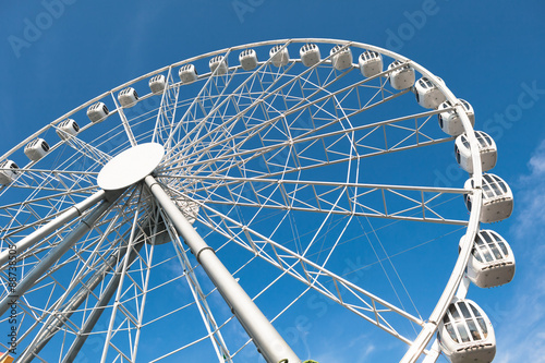 modern white ferris wheel against blue sky background