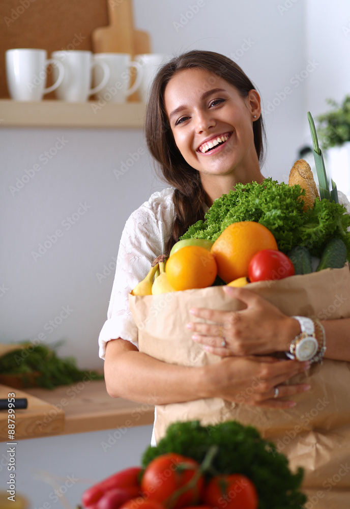 Young woman holding grocery shopping bag with vegetables and Young woman holding grocery shopping bag with vegetables and