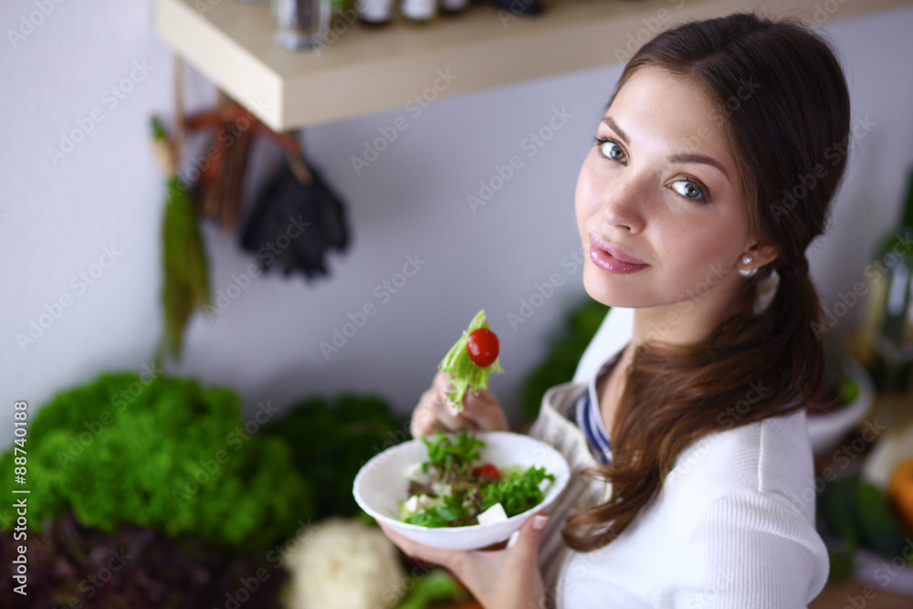 Young woman eating salad and holding a mixed salad Young woman eating salad and holding a mixed salad