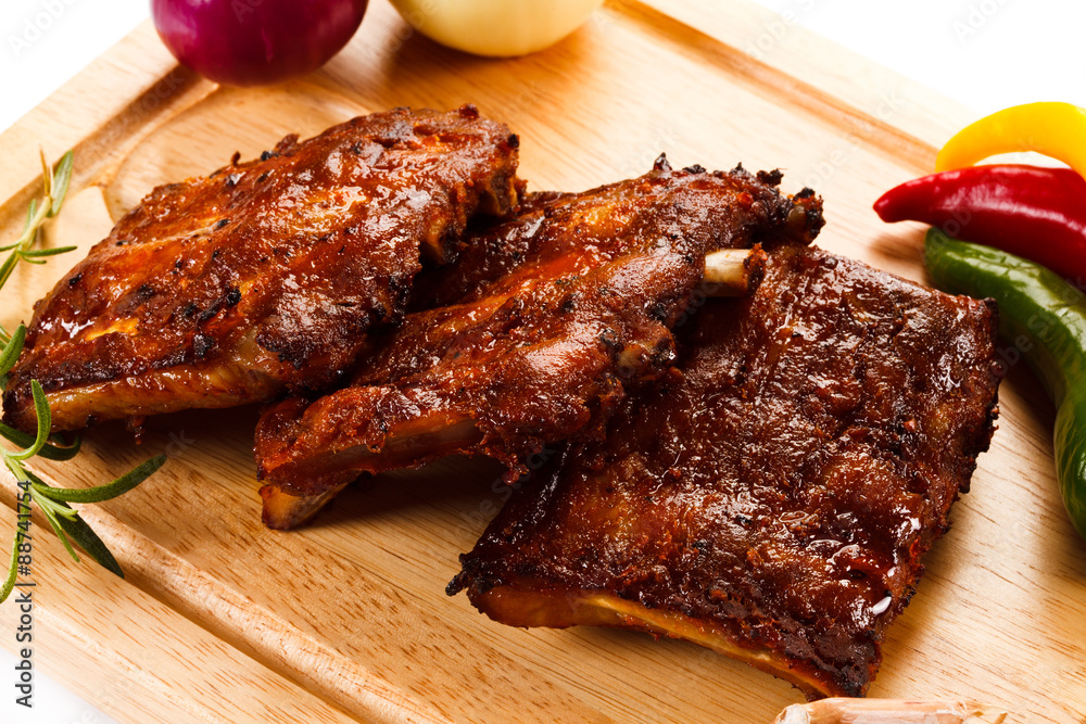 Barbecued ribs with vegetables on cutting board 