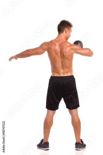 Kettlebell Workout. Rear view of muscular man holding a kettlebell on his shoulder. Full length studio shot isolated on white.