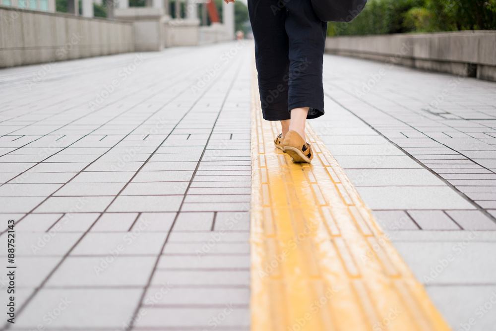 歩道の誘導ブロックを歩く女性 歩道の誘導ブロックを歩く女性