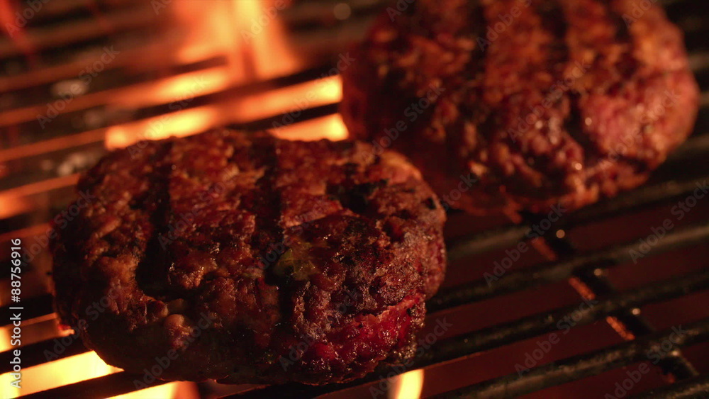 Beef burger patties cooking on the grill of a barbecue