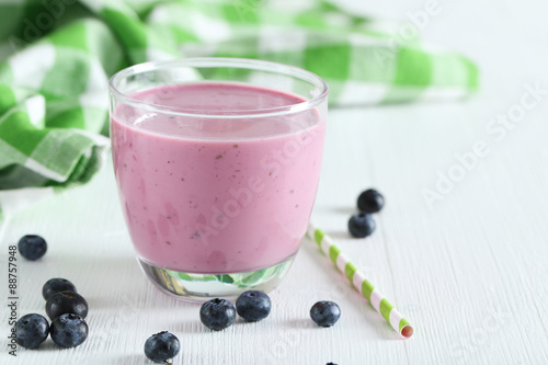 Fresh blueberry smoothie in the glass on white wooden background