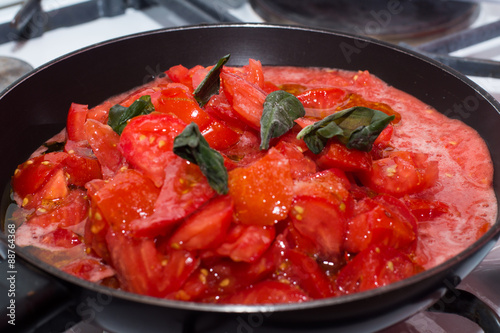 Sugo di pomodoro fresco in cottura, padella sul fuoco, fornelli