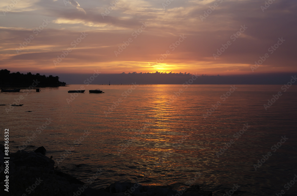 beautiful sunset at seaside with silhouette of boats horizontally cropped