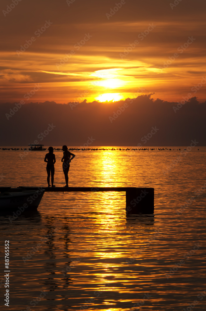 sea and pier at a beautiful sunset with a silhouette of people