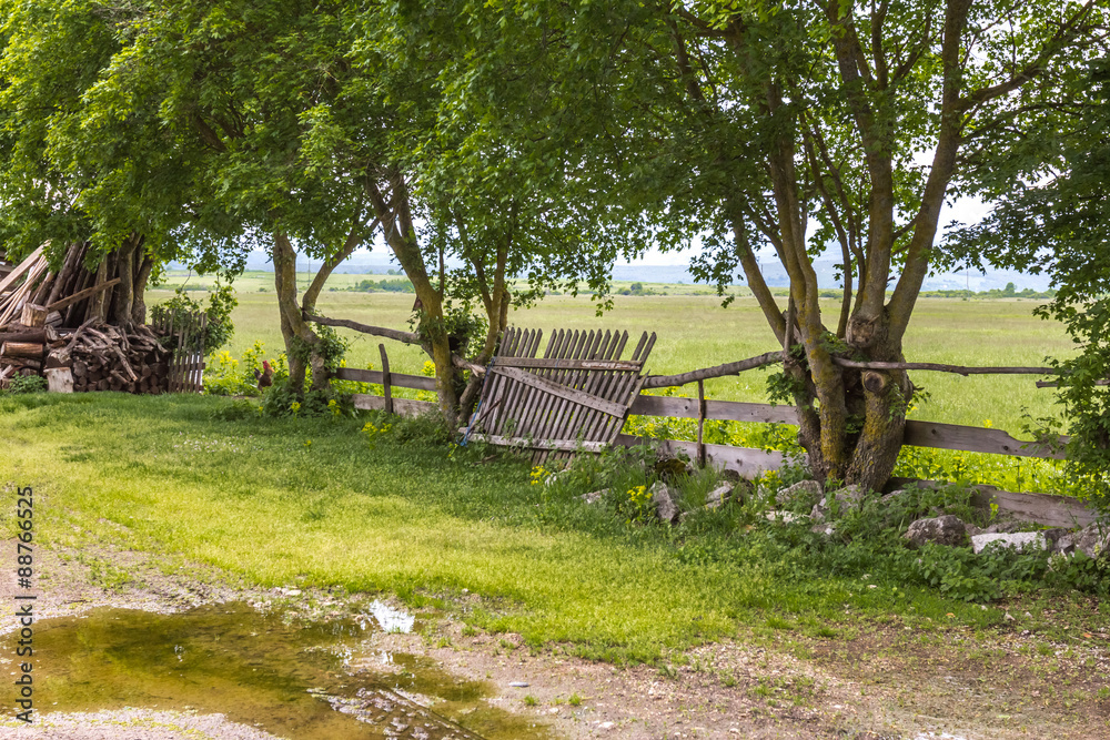 Wooden board fence part rests on other log fence at croatian farm in spring