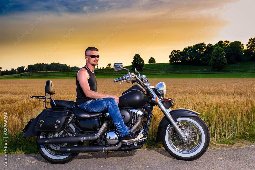 Obraz premium Tough guy with his bike in front of a corn field