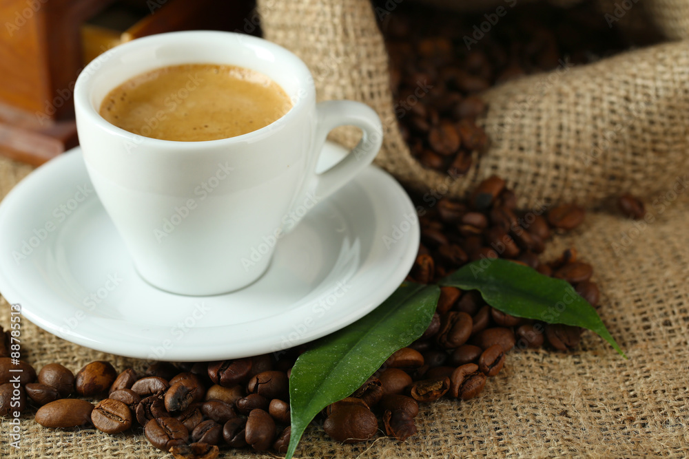 Cup of coffee with beans on table close up