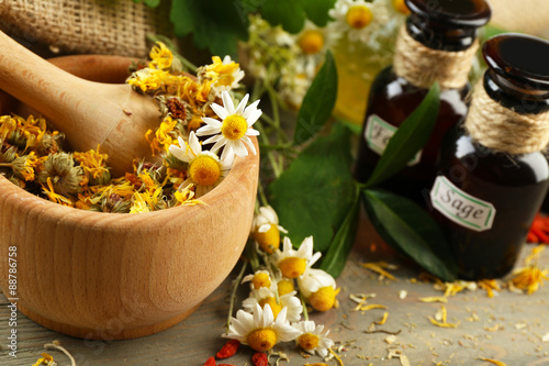 Fototapeta Naklejka Na Ścianę i Meble -  Herbs, berries and flowers with mortar, on wooden table background