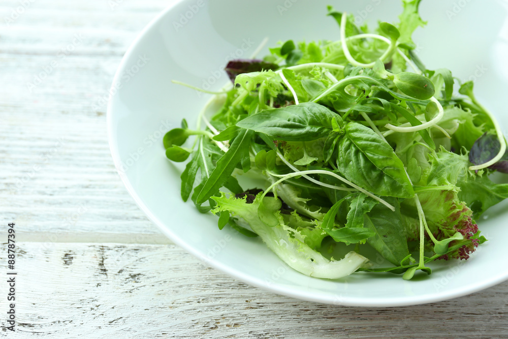 Fresh mixed green salad in bowl on wooden table close up Fresh mixed green salad in bowl on wooden table close up
