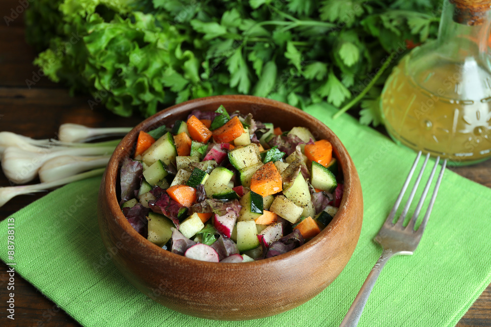 Wooden bowl of fresh vegetable salad on napkin, closeup Wooden bowl of fresh vegetable salad on napkin, closeup