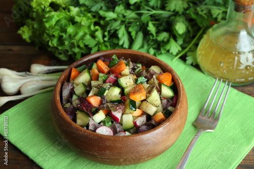 Wooden bowl of fresh vegetable salad on napkin, closeup