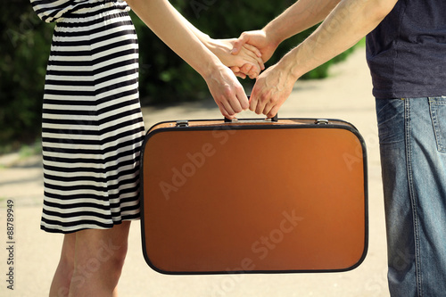 Young couple holding vintage suitcase outdoors