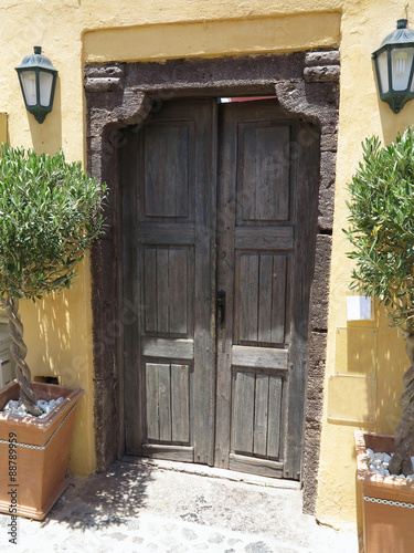 Old brown wooden door and lamps in Greece