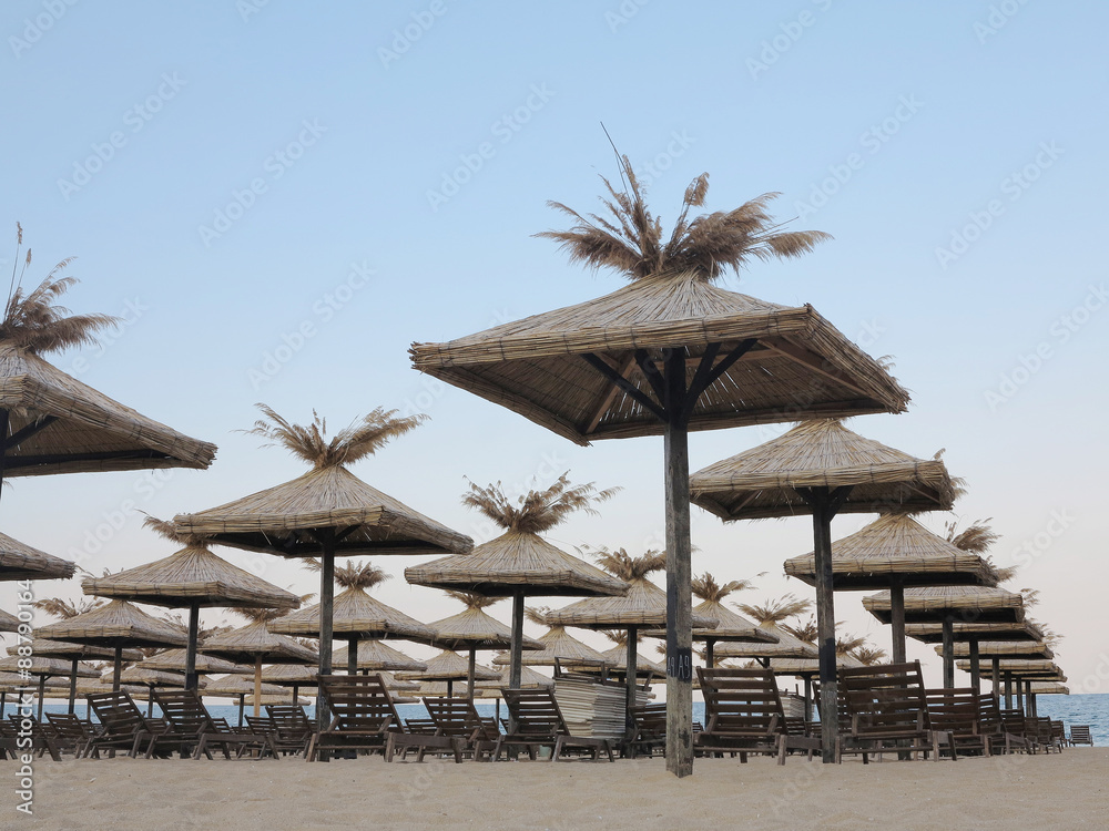 Beach chairs and umbrella on the sand near sea, blue sky