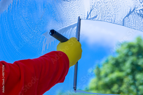 Hand cleaning window with blue sky and white clouds photo